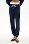 A model wears the SPLITS59 Andie Dual Waist Sweatpant in Indigo/White, crafted from ultra-luxe fleece with a contrasting white drawstring and white waistband. Styled with black ballet flats and photographed against a plain white background, these sweatpants are proudly made in Los Angeles.