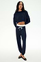 A woman stands against a plain white background wearing the SPLITS59 Andie Dual Waist Sweatpant in Indigo/White, crafted from ultra-luxe fleece and featuring a white drawstring. Made in Los Angeles.