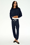 A woman stands against a plain white background wearing the SPLITS59 Andie Dual Waist Sweatpant in Indigo/White, crafted from ultra-luxe fleece and featuring a white drawstring. Made in Los Angeles.