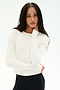 A person with long braided hair models the SPLITS59 Airweight Lite Long Sleeve Waist Length tee in white, paired with black pants, posing with one hand touching their face against a plain white background.