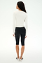 A woman stands facing away from the camera, wearing the SPLITS59 Airweight Lite Long Sleeve Waist Length top in white, paired with black knee-length leggings ideal for gym workouts and white sneakers, against a plain white background.