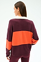 A woman faces away, wearing the SPLITS59 Katie Fleece Rugby in Dark Cherry/Valencia—a long-sleeve top with wide maroon and orange stripes—paired with maroon modal-spandex leggings.