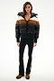 A woman wears the SPLITS59 Aspen Puffer Jacket - Black/Toffee, black flared pants with side stripes, and brown boots against a white background.