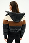 Woman facing away in the SPLITS59 Aspen Puffer Jacket - Black/Toffee, a nylon color-blocked puffer with black, brown, and cream stripes, filled with white duck down, paired with black pants.