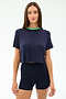 A woman faces forward in the SPLITS59 Djuna Crop Ringer - Indigo/Spearmint, a navy cropped tee with green collar, paired with navy fitted viscose shorts, posed against a plain white background.