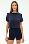 A woman faces forward in the SPLITS59 Djuna Crop Ringer - Indigo/Spearmint, a navy cropped tee with green collar, paired with navy fitted viscose shorts, posed against a plain white background.