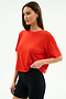 A woman stands against a plain white background, ready for gym workouts in the SPLITS59 Djuna Oversized Jersey Tee in Lotus Red and black fitted shorts.