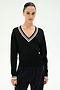 A woman models the SPLITS59 Jemma Knit V Neck in Black/White—a soft nylon-rayon blend sweater featuring a black hue with white stripes on the collar and cuffs—paired with black pants against a plain light background.