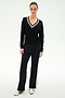 A person stands against a plain background wearing the SPLITS59 Jemma Knit V Neck in Black/White, expertly crafted from a soft rayon-nylon blend, paired with black wide-leg pants featuring a white side stripe and crisp white sneakers.