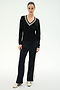 A person stands against a plain background wearing the SPLITS59 Jemma Knit V Neck in Black/White, expertly crafted from a soft rayon-nylon blend, paired with black wide-leg pants featuring a white side stripe and crisp white sneakers.