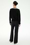 A person with dark hair in a bun stands facing away, wearing the SPLITS59 Jemma Knit V Neck in Black/White—a long-sleeve top paired with wide-leg black pants featuring white side stripes, all crafted from soft rayon fabric—against a plain white background.