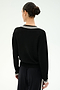 A person stands facing away, wearing the SPLITS59 Jemma Knit V Neck in Black/White paired with black soft rayon pants. Their hair is tied back in a neat bun, and the background is plain white.
