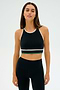 A person wearing the SPLITS59 Layla Airweight Bra in Black/Arugula stands against a plain background, fully dressed in an athletic ensemble.