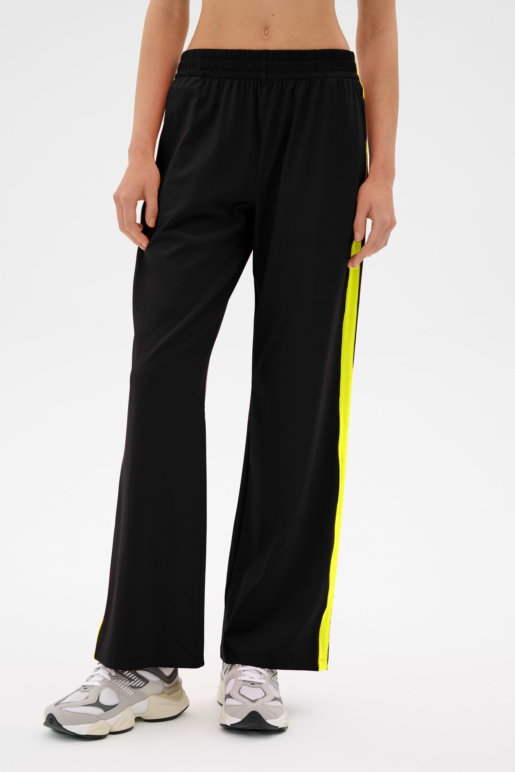 A person wearing the SPLITS59 Maxie Rigor Track Pant with gray sneakers stands against a plain background.