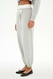 A person wears the SPLITS59 Andie Dual Waist Sweatpant in Heather Grey/White, featuring a white drawstring, paired with a gray top and black ballet flats, standing against a white background.