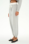 A person wears the SPLITS59 Andie Dual Waist Sweatpant in Heather Grey/White, featuring a white drawstring, paired with a gray top and black ballet flats, standing against a white background.