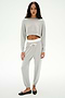 A woman faces forward wearing the SPLITS59 Noah Fleece Crop Sweatshirt in Heather Grey, styled with matching joggers featuring a white drawstring and black flats.