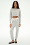 A woman stands against a plain background wearing SPLITS59's Andie Dual Waist Sweatpant in Heather Grey/White—soft modal blend joggers with a drawstring—paired with a light grey cropped sweatshirt and black ballet flats.