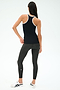 A woman faces away, wearing the SPLITS59 Ashby Rib Tank in Black/White, paired with dark gray leggings and white sneakers—ideal activewear for gym sessions against a plain background.