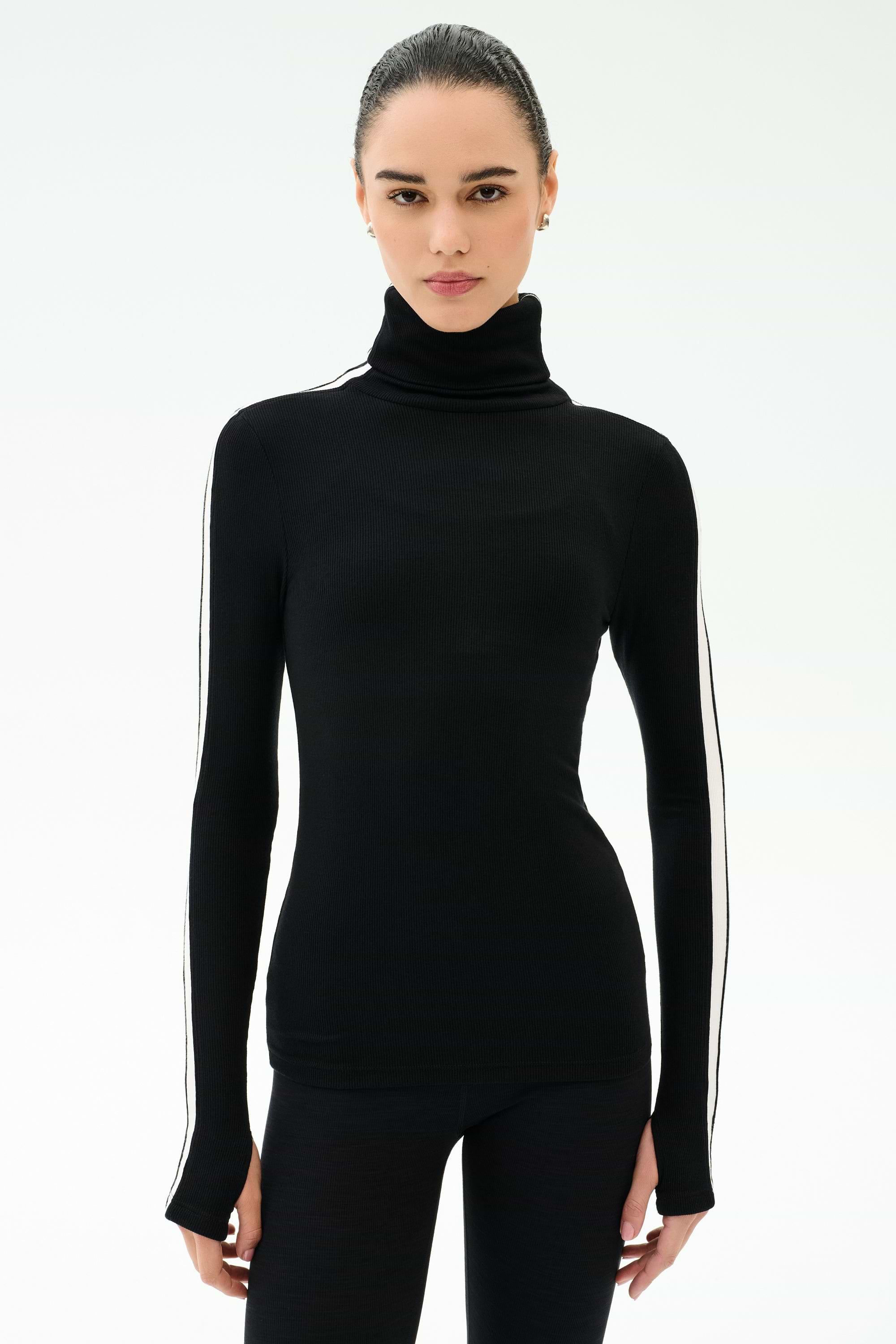 A woman faces forward against a white background, wearing the SPLITS59 Jackson Rib Full Length Turtleneck in Black/White with matching black pants.