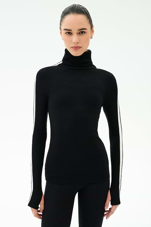 A woman faces forward against a white background, wearing the SPLITS59 Jackson Rib Full Length Turtleneck in Black/White with matching black pants.