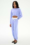 A person stands against a white background wearing the SPLITS59 Noah Fleece Crop Sweatshirt in Purple Haze with matching sweatpants, both made from stretchy material, styled with black ballet flats.