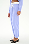 A person wears SPLITS59's Andie Dual Waist Sweatpant in Purple Haze/White with a matching long-sleeve top and black ballet flats, standing against a plain white background.