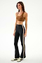 Woman wearing a brown spandex sports bra, SPLITS59 Raquel High Waist Supplex Flare - Black/Creme pants, and white Adidas sneakers against a plain white background.