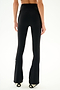Model wearing SPLITS59 Raquel High Waist Supplex Flare - Black/Creme pants and black-and-white shoes, seen from the back against a plain white background.