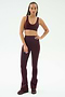 A person stands facing forward, wearing SPLITS59's Raquel High Waist Flared Legging in Dark Cherry/Creme with a matching sports bra and sneakers, set against a plain white background.