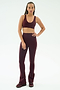 A person stands facing forward, wearing SPLITS59's Raquel High Waist Flared Legging in Dark Cherry/Creme with a matching sports bra and sneakers, set against a plain white background.