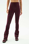 A person wearing SPLITS59 Raquel High Waist Flared Legging in Dark Cherry/Creme, paired with matching burgundy athletic shoes, shown from shoulders down against a plain background.