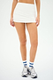 Wearing the Sally Rigor Skort in white by SPLITS59, paired with white socks featuring blue stripes and sleek white sneakers, this outfit is perfect for high-impact workouts against a plain backdrop.
