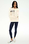 A person stands against a plain white background wearing the SPLITS59 Stella French Terry Oversized Hoodie in creme, featuring "Splits59 Los Angeles" text, paired with navy blue leggings and white sneakers.