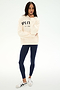A person stands against a plain white background wearing the SPLITS59 Stella French Terry Oversized Hoodie in creme, featuring "Splits59 Los Angeles" text, paired with navy blue leggings and white sneakers.