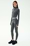 A woman wears the SPLITS59 Bailey Active Rib High Waist 7/8 leggings in Heather Grey with a fitted, long-sleeve top and black sneakers, standing against a plain white background.