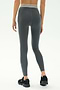 A person faces away, wearing SPLITS59 Bailey Active Rib High Waist 7/8 leggings in Heather Grey with a white-striped waistband and black sneakers, set against a plain background—ideal for gym workouts.