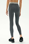 A person faces away, wearing SPLITS59 Bailey Active Rib High Waist 7/8 leggings in Heather Grey with a white-striped waistband and black sneakers, set against a plain background—ideal for gym workouts.
