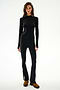 Woman in SPLITS59 Isabelle Airweight Lite Mock Neck - Black/Creme, paired with matching flared pants and brown boots, stands against a white background.