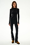 Woman in SPLITS59 Isabelle Airweight Lite Mock Neck - Black/Creme, paired with matching flared pants and brown boots, stands against a white background.