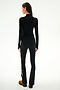 A person faces away wearing the SPLITS59 Isabelle Airweight Lite Mock Neck - Black/Creme, black side-striped pants, and brown shoes against a plain white background.