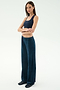A woman stands with arms crossed, wearing the SPLITS59 Joy Velour Pant in Indigo and a navy crop top, paired with black shoes against a plain light background.