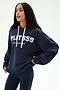 A person wearing the Stella French Terry Oversized Hoodie in indigo by SPLITS59, featuring "SPLITS59 Los Angeles" text and crafted from soft cotton fabric, paired with navy leggings while standing against a plain light background.