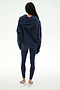 Standing with back to camera, the person is wearing the SPLITS59 Stella French Terry Oversized Hoodie in Indigo, paired with navy leggings and white sneakers against a plain white background.