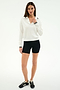 A woman faces forward against a plain white background wearing the SPLITS59 Taylor Knit Polo in White/Black.