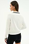 A woman with straight brown hair wears the SPLITS59 Taylor Knit Polo in white/black, paired with black shorts, standing with her back to the camera against a plain background.