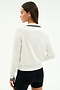 A woman with straight brown hair wears the SPLITS59 Taylor Knit Polo in white/black, paired with black shorts, standing with her back to the camera against a plain background.