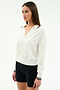 A woman poses against a plain background wearing the SPLITS59 Taylor Knit Polo in white with black stripes, featuring long sleeves and a collared design, styled with fitted black shorts.
