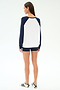 A person stands facing away, wearing the SPLITS59 Andie Oversized Colorblock Fleece in Indigo/White, black shorts, and white sneakers with navy stripes, against a plain white background.