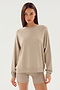 A person with long straight hair, dressed in an Andie Fleece Sweatshirt - Latte by SPLITS59 and matching shorts made from stretch modal fabric, stands against a plain white background.